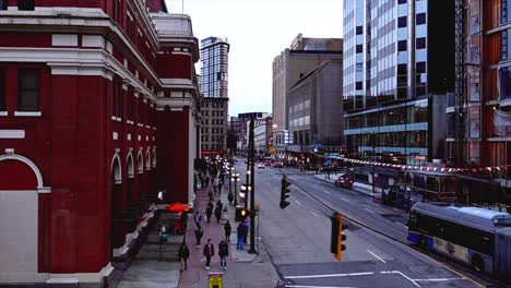 pan-left-shot-of-Downtown-Vancouver-with-people-walking-on-the-sidewalks-and-a-bus-driving-down-Waterfront-Road