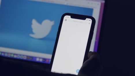 A-computer-and-smartphone-screen-show-the-Twitter-logo-as-a-finger-in-silhouette-scrolls-through-political-tweets