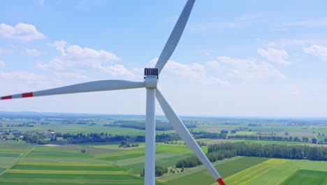 Renewable-energy-wind-turbine-spinning-on-green-agricultural-farmland-generating-power,-Aerial-view