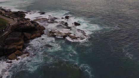 High-drone-shot-of-rocks-being-lapped-with-waves