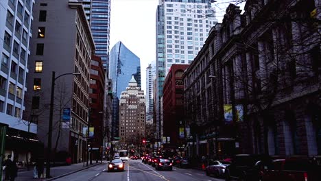 Pan-right-shot-of-west-hastings-street-in-Downtown-Vancouver-with-people-walking-on-the-sidewalks-on-an-overcast-day