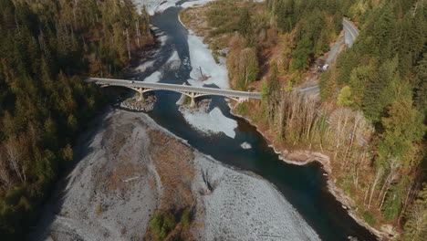 Aerial-view-of-beautiful-american-mountain-river-flowing-between-rocks-and-below-bridge