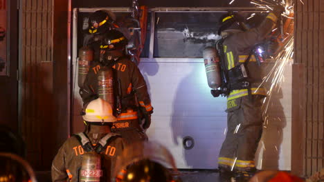 Die-Feuerwehr-Von-Toronto-Schnitt-Spät-In-Der-Nacht-Mit-Rettungssägen-In-Das-Garagentor,-Wobei-Funken-Flogen