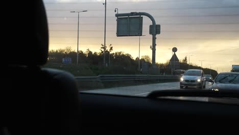 Golden-Sunset-Skies-Seen-From-Back-Window-Of-Car-Driving-Along-Motorway-In-London