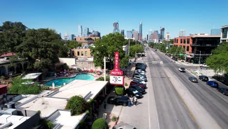 Aerial-drone-backward-moving-shot-over-tourists-entering-Austin-Motel-in-Texas,-USA-on-sunny-day