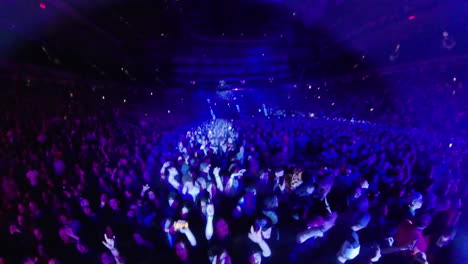Insta-360-Wide-Angle-View-of-Spectators-Crowd-Dancing-Cheering-During-Indoor-Music-Performance-Show,-Colorful-Spotlights-and-Arena-Stands-Around