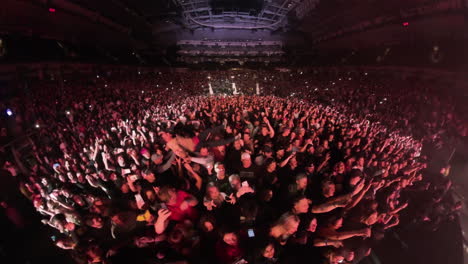 Insta-360-Wide-Angle-View-of-Mosh-Pit-Scene,-Spectators-Crowd-in-Front-of-Stage-Dancing-Cheering-Carrying-Man-on-Arms-at-Rock-Music-Concert-Show,-Inside-Arena-Panoramic-View-With-Colorful-Spotlights