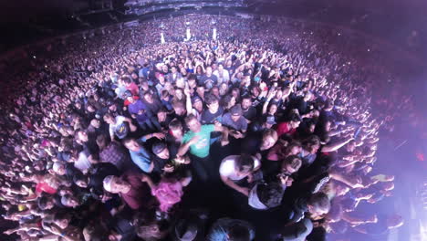 Insta-360-Wide-Angle-View-of-Mosh-Pit-Scene,-Spectators-Crowd-in-Front-of-Stage-Jostling-Dancing-Cheering-at-Rock-Music-Concert-Show,-Colorful-Spotlights