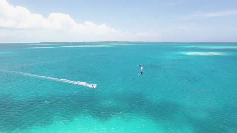 Drone-shot-FOLLOWING-ONE-MAN-KITESURF-IN-FLAT-WATER-CARIBBEAN-SEA,-LOS-ROQUES