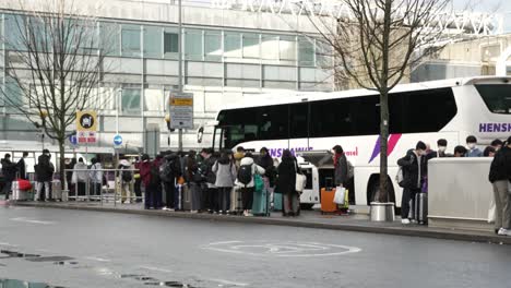 6-November-2022---Group-Of-Passengers-Waiting-Beside-Coach-At-Drop-Off-Point-At-Heathrow-Terminal-3