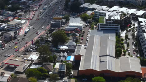Aerial-shot-of-Australianbusy-suburb-by-bridge-with-river-heavy-traffic-on-roads-with-cars-and-businesses
