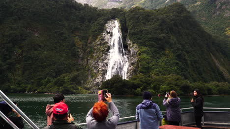 Shot-of-tourists-taking-photos-from-phone-while-passing-by-lady-bowens-falls-in-Southland,-south-island,-Fiordland-national-park,-Milfird-Sound,-New-Zealand-at-daytime