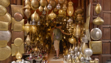 Turistas-Navegando-Por-El-Interior-De-La-Tienda-De-Lámparas-Tradicionales-En-El-Mercado-De-Marrakech,-Marruecos