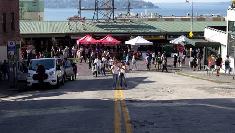 Famous-Pike-Market-Place-crowded-with-people-in-Seattle-Washington,-middle-of-the-street-two-women-taking-a-selfie