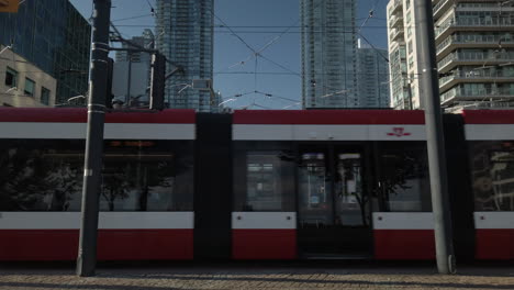Exterior-shot-of-red-streetcar-moving-through-frame-as-cyclists-pass-by-in-the-foreground