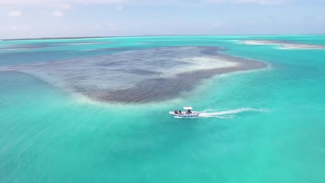 Motor-BOAT-SAILING-ON-PRISTINE-NATURAL-PARK-WITH-KITRESURFERS-ON-BOARD,-Drone-shot-los-Roques