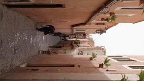 Vertikale-Aufnahme-Der-Schmalen-Straße-Von-Marrakesch-In-Marokko-Mit-Vorbeigehenden-Menschen