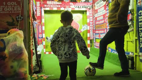 Young-boy-having-fun-at-Penalty-kick-mechanical-attraction-in-Funfair,-San-Froilán-carnival