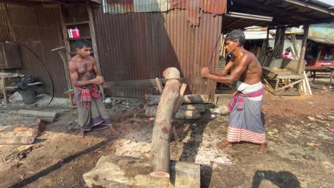 Two-worker-man-sawing-wood-by-blade-in-hand-at-timber-cutting-factory-in-Bangladesh