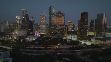 Aerial-view-in-front-of-thr-illuminated-Houston-skyline,-dusk-in-Texas,-USA---circling,-drone-shot