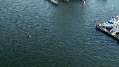 Drone-shot-of-someone-riding-an-electric-surfboard-by-Lake-Union's-docks