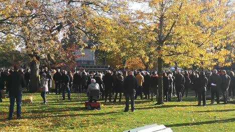 People-gathering-at-public-UK-park-memorial-Cenotaph-paying-respect-on-remembrance-Sunday-service