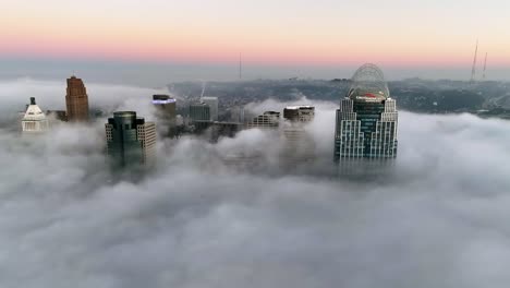 Aerial-view-in-front-of-downtown-Cincinnati,-foggy-sunrise-in-Ohio,-USA---tracking,-drone-shot
