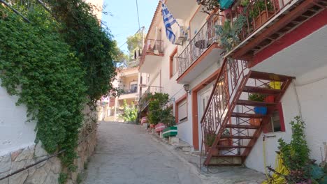 Greek-National-Flag-waving-on-picturesque-alley,-Parga,-Greece