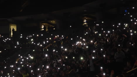 Spectators-Crowd-in-Arena-Stands-Holding-Luminous-Phones-and-Lights-During-Music-Concert-Show,-Lights-in-Dark,-Romantic-Atmosphere