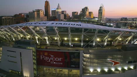 Aerial-view-over-the-Paycor-Stadium,-towards-the-Cincinnati-skyline,-sunset-in-Ohio,-USA---rising,-drone-shot