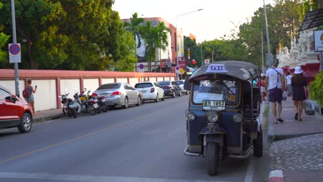Típico-Tuk-Tuk-Tailandés-Estacionado-Al-Lado-De-La-Carretera-Con-Gente-Caminando