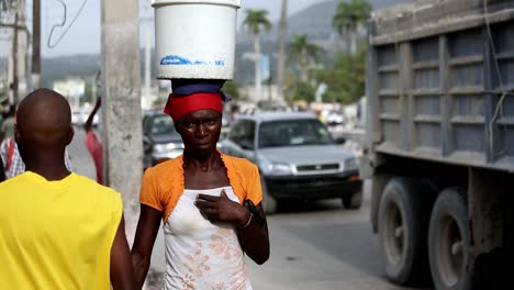 Focused-close-up-of-a-black-woman-carrying-a-bucket-on-her-head-in-the-street