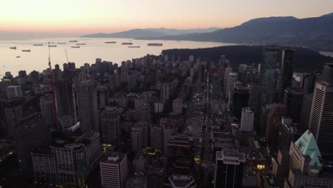 Aerial-view-over-the-cityscape-of-downtown-Vancouver,-sundown-in-BC,-Canada---reverse,-drone-shot