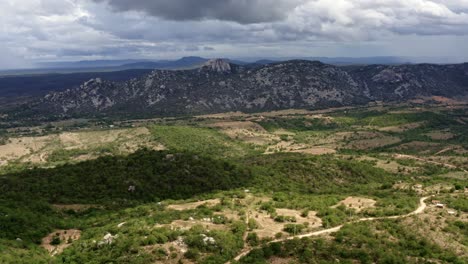 Tilting-up-aerial-drone-extreme-wide-shot-of-the-mountain-range-of-the-Pedra-de-Sao-Pedro-in-Sítio-Novo,-Brazil-in-the-state-of-Rio-Grande-do-Norte-in-the-countryside-with-rural-homes-and-farmland