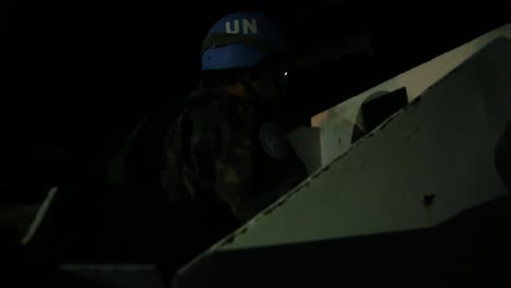Soldat-Der-Vereinten-Nationen-Auf-Der-Rückseite-Eines-Gepanzerten-Fahrzeugs,-Das-Nachts-Patrouilliert