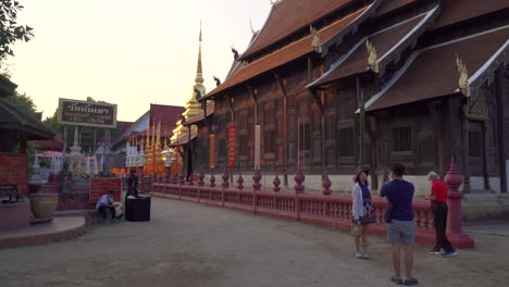 Tourists-taking-selfies-at-Thai-wooden-temple-at-sunset