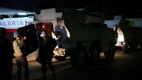 Unit-of-armed-members-of-the-United-Nations-on-a-mission-next-to-an-armored-vehicle-on-the-street-at-night