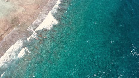 Drone-shot-tilt-up-reveal-scenic-crashing-waves-on-barrier-reef,-los-roques