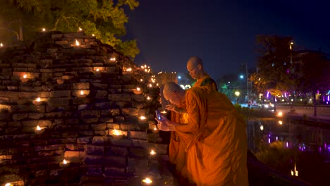 Two-young-Thai-monks-in-Orange-robes-taking-pictures-of-candles-during-Yi-Peng-Festival