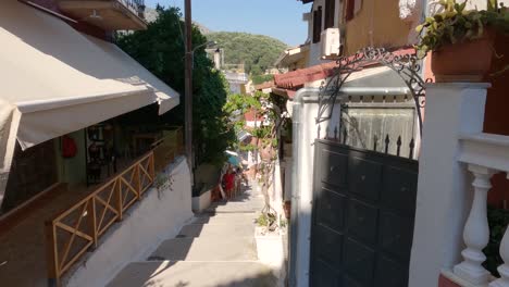 People-walking-up-slope-of-charming-alley-in-Parga,-Greece