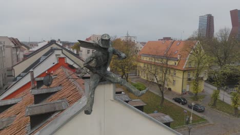 An-aerial-view-A-bronze-sculpture-of-a-happy-chimney-sweep-is-placed-on-the-edge-of-the-building's-roof-in-Klaipeda-city
