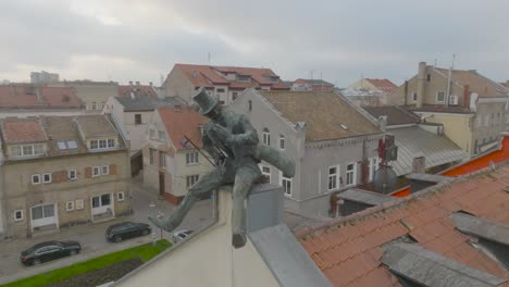 An-aerial-view-A-bronze-sculpture-of-a-happy-chimney-sweep-is-placed-on-the-edge-of-the-building's-roof-in-Klaipeda-city