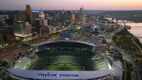 Aerial-view-overlooking-the-Paycor-Stadium-and-downtown-Cincinnati,-dusk-in-Ohio,-USA---rising,-tilt,-drone-shot