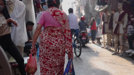 Slow-motion-following-a-woman-dressed-in-a-sari-walking-through-the-streets-of-Kathmandu,-Nepal