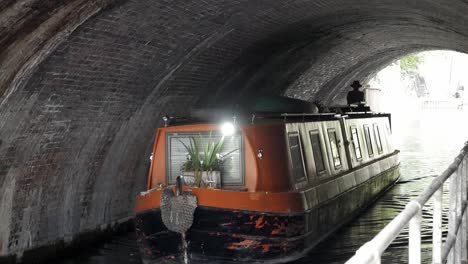 Narrowboat-sailing-under-tunnel-in-London-canal-during-daylight