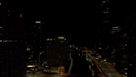The-downtown-Chicago,-Illinois-district---aerial-flyover-above-the-Chicago-River-at-nighttime