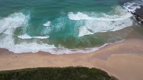 Waves-crashing-on-empty-beach-aerial-Lake-Conjola,-Australia