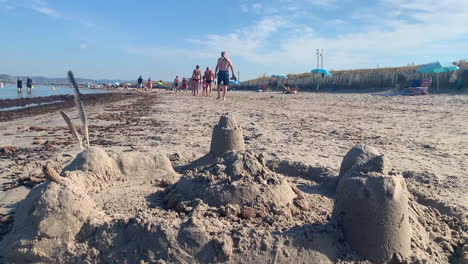Sandcastle-and-sand-figures-with-people-walking-in-the-background