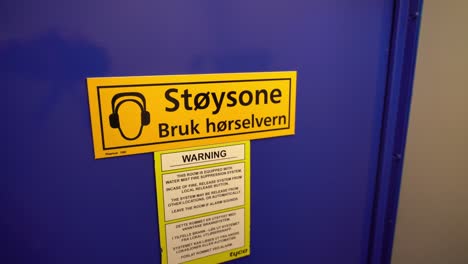 Sign-warning-about-noise-zone-on-door-to-ships-engine-room---Norwegian-language-on-sign