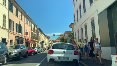 People-walking-along-the-road-in-between-shopping-buildings,-St-Tropez
